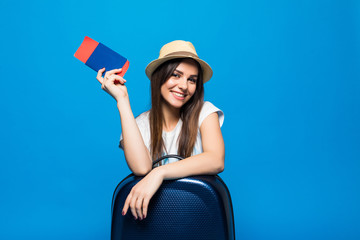 Young woman with blue suitcase and ticket passport on blue background
