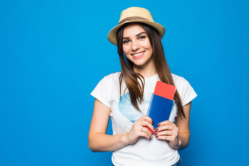 Portrait of a cheerful cute girl traveller in summer clothes showing passport with tickets to camera isolated over blue background