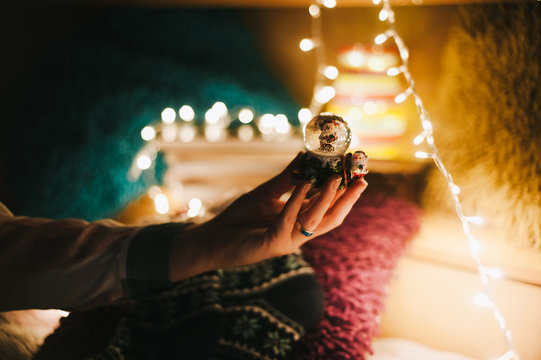 Christmas Mood. Woman Holding A Snowglobe With New Year Bulbs In Background.