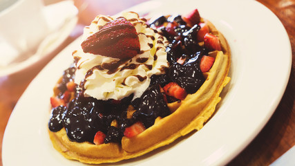 Delicious homemade waffle desert with fruits and whip creame