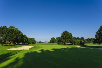 Fototapeta premium General view of a green golf course on a bright sunny day. Idyllic summer landscape. Sport, relax, recreation and leisure concept