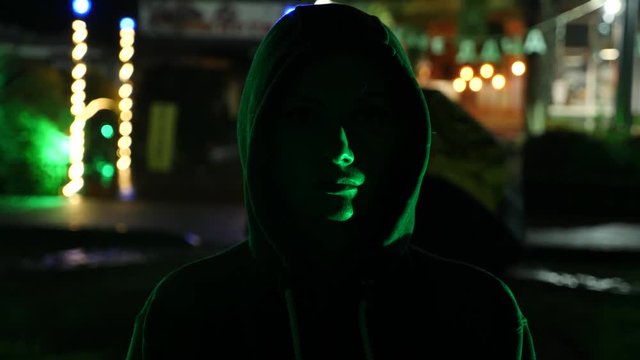 Silhouette of a man in a hood standing on a night street. 4k