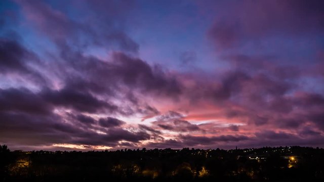 Timelapse of colourful clouds over suburban skyline at New Hall Valley Country Park during sunset in Birmingham, England.