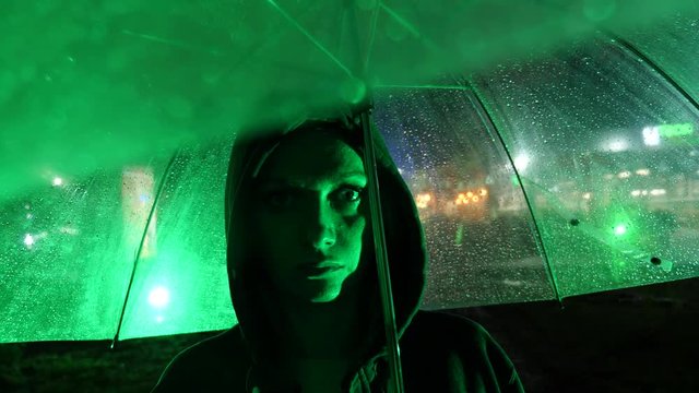Silhouette of a man in a hood standing on a night street. 4k
