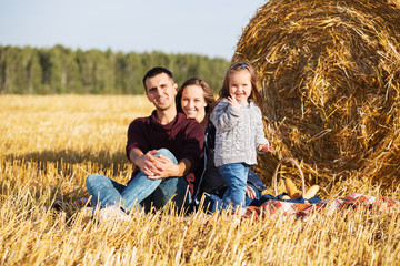 Naklejka na ściany i meble Happy young family with 2 year old girl next to hay bales in harvested field