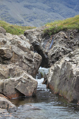 A rock wedged between two stone faces with water flowing against