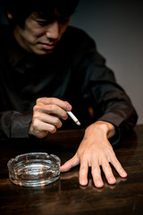 タバコを手に押し付けようとする男性