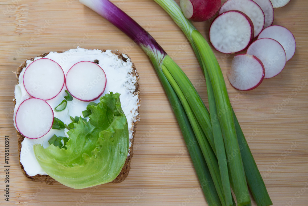 Wall mural sandwich with vegetables, herb and cream cheese on wooden table. radish, green onion, salad, bread w