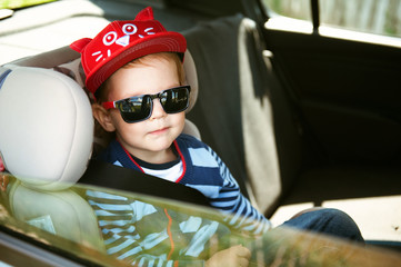 Portrait of cute toddler boy sitting in car seat. Child transportation safety.