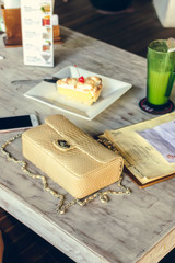 Fototapeta na wymiar Fashion luxury snakeskin python handbag on the wooden table in restaurant. Bali island.
