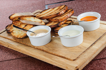 Slice of toast roasted in breaded with cheese and sesame slipped in a sauce on a wooden board