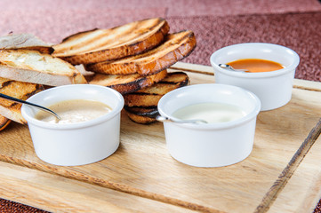 Slice of toast roasted in breaded with cheese and sesame slipped in a sauce on a wooden board