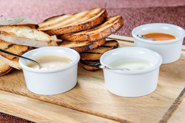 Slice of toast roasted in breaded with cheese and sesame slipped in a sauce on a wooden board