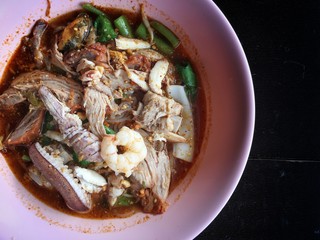 Noodles seefood Tom yum with squid and mantis shrimp, squid, prawn in a bowl on wooden table, still life and Thai style food.