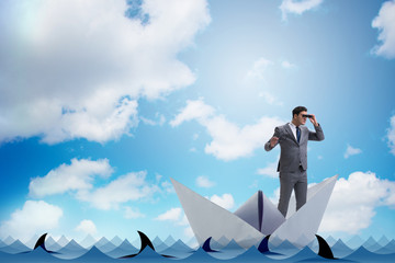 Obraz premium Businessman looking into future with binoculars in paper ship bo