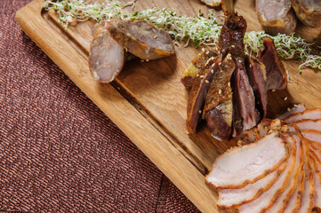Baked goose leg in berry sauce on a wooden plate .