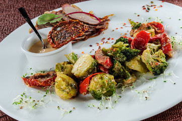 Slised meat meal with vegetables on white plate