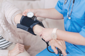 Close up of female doctor checking pressure of elderly patient