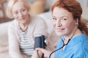 Radiant female doctor with sphygmomanometer smiling into camera