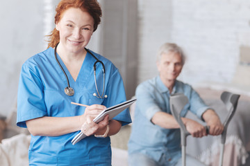 Positive minded medical worker smiling while taking notes