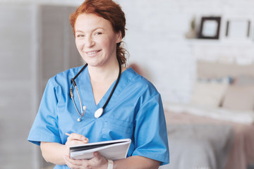 Friendly looking nurse with notebook smiling into camera