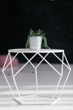 Loft design geometric white table with flower in bucket pot isolated on black background. Modern interior concept