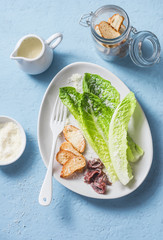 Classic Caesar salad. Romano salad with anchovies, parmesan, croutons and caesar dressing on a blue background, top view