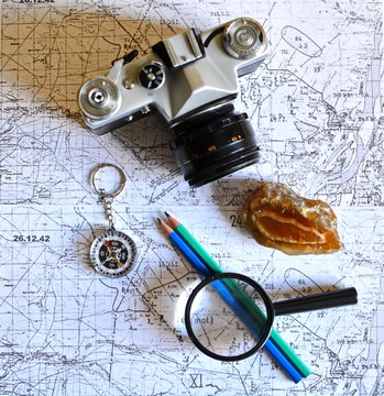 pencil, vintage photo camera, mineral stone, magnifier and compass on old military topographical map
