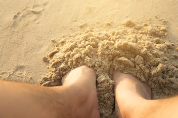 Picture of a foot buried in the sand at the beach.
