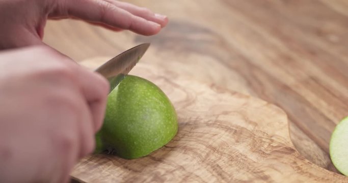 Slow motion young female hands cut green apple