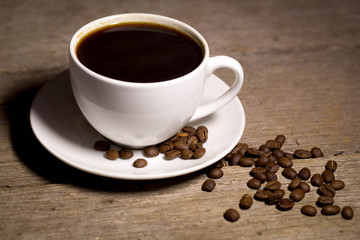 Coffee in cup with coffee beans with wooden background in studio
