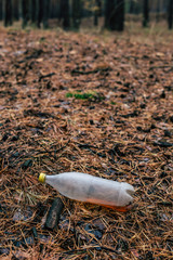 Plastic white bottle on the ground in the pine forest
