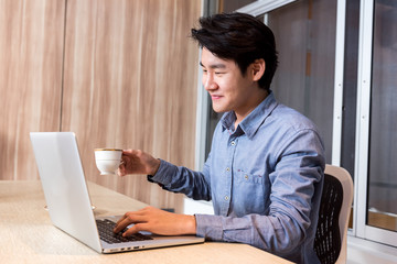 Fototapeta premium Businessman hand holding coffee cup and working in the Office with labtop Concept.