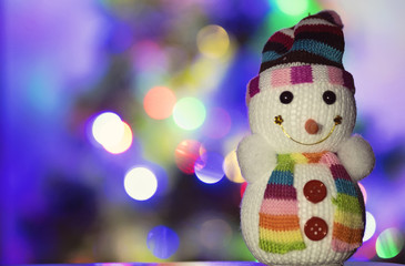 Toy snowman and Christmas lights in the background