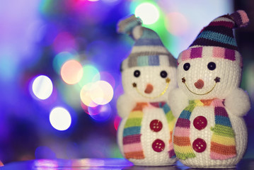 Toy snowman and Christmas lights in the background