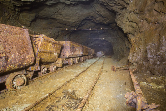 Underground mine shaft gold copper ore tunnel gallery with rails and ore carts wagons