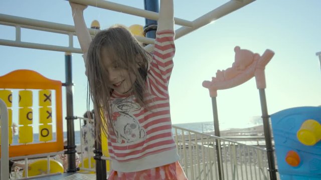 Happy girl keeps the street workout bars above her and smiles on a sea shore in slo-mo