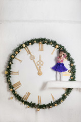 Beautiful little girl on a big New Year's clock. Child in Christmas decorations.