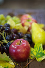 Naklejka na ściany i meble Seasonal autumn fruits with leaf on a wooden background. Apple in focus