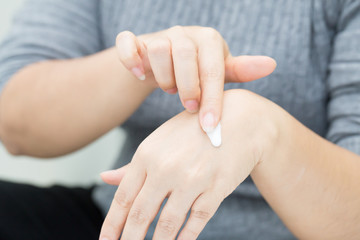 Woman takes care of hand using cosmetic cream