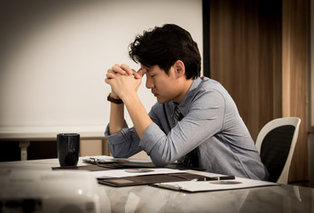 Obraz premium businessman having a hard time with coin stack, calculator and document graphic on the table, he holding his head in his hands.