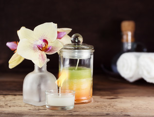 Spa set on wooden table. Yellow orchid and layered candle. White towels in background. Relax, massage concept. Text space