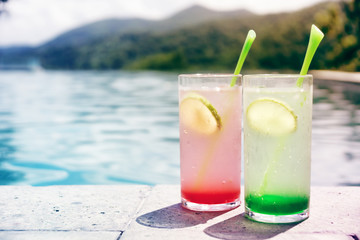 two cocktails, red and green, at pool side. Vacation, relax concept. Text space