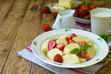 Sweet berry breakfast. Sweet lazy pierogi, dumplings with sour cream, butter and strawberry on wooden background. Italian gnocchi. Copy space for your text