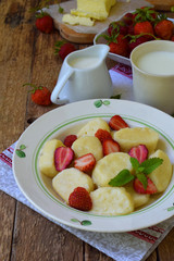 Sweet berry breakfast. Sweet lazy pierogi, dumplings with sour cream, butter and strawberry on wooden background. Italian gnocchi. Copy space for your text