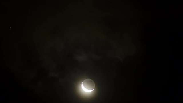 Timelapse of young moon mooving through clouds at night