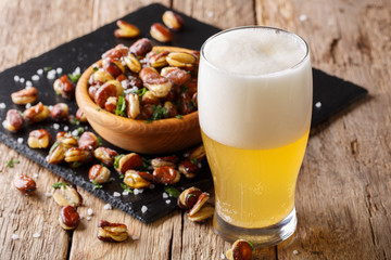 glass of light beer with appetizer from crispy fried salted broad beans close-up. horizontal