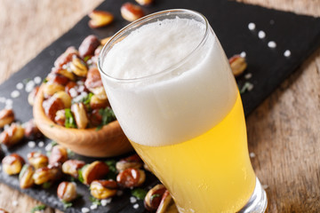 glass of light beer and crispy fried salted beans macro on a table. horizontal