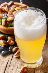 Light beer with foam and fried salted broad beans close-up. vertical