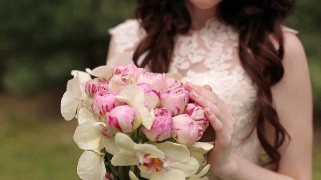 Bride in lace dress holding beautiful white wedding flowers bouquet, close-up.